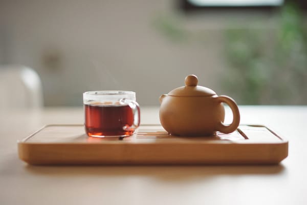 tea set with glass mug of tea next to a teapot